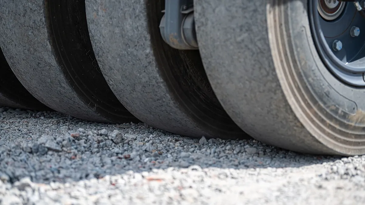 Roller tires compacting fresh gravel during a driveway repair